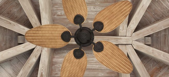 A view looking up at a rustic wood ceiling with a bamboo ceiling fan.