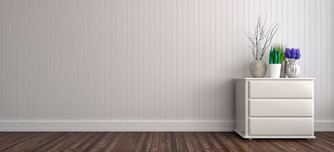 A wall with wainscoting and a dresser decorated with vases