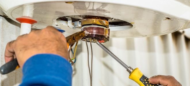 hands with tools working on electric water heater