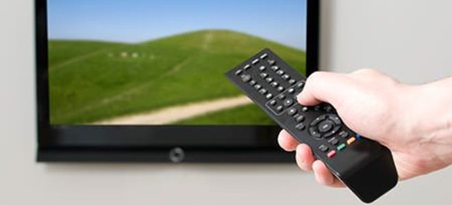 Hand holding a remote aimed at a TV