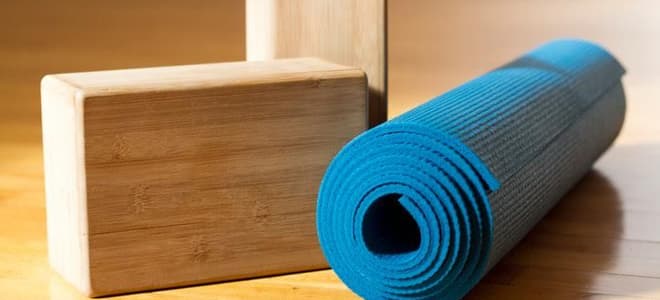 A blue yoga mat and two wood yoga blocks. 
