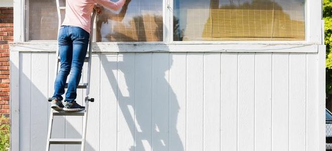 Woman on a ladder painting garage door