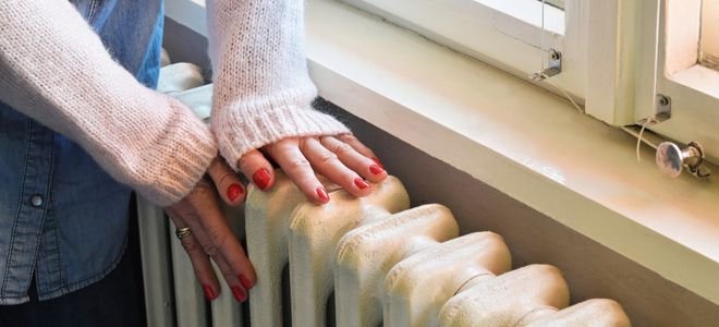 Person’s hands on a wall radiator