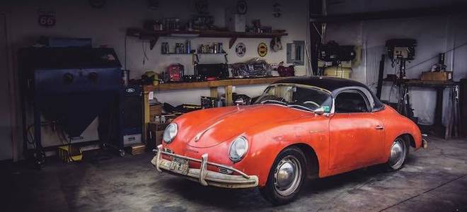 A concrete garage floor with a red car on it.