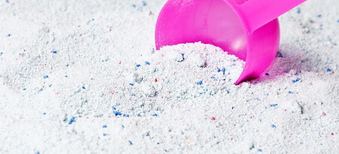 Powdered laundry detergent scooped with a pink handle.