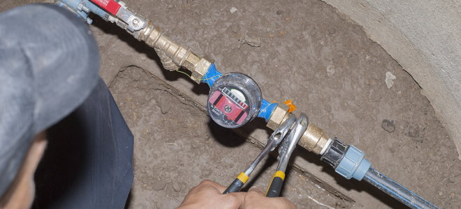 A man adjusts a water meter.