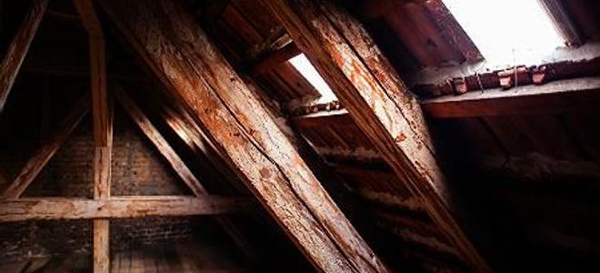 The corner of an old attic with windows on the near wall.