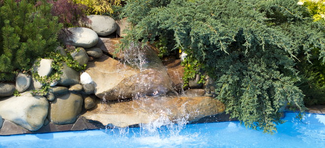 Rock waterfall with plants by a pool