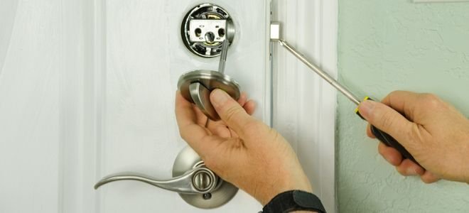 hands installing disassembled deadbolt lock