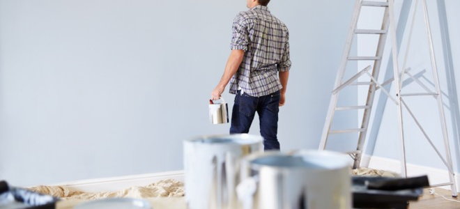 man painting a wall light grey