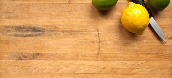 Lemons and limes next to a knife on a cutting board.