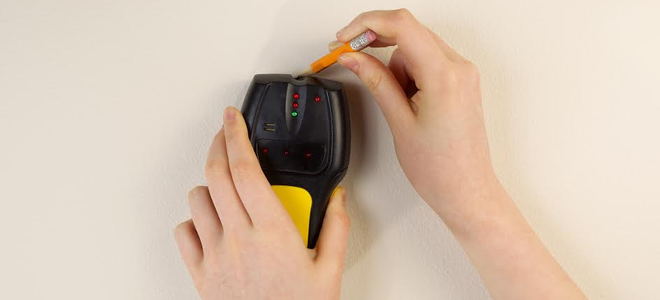 using a stud finder on a wall