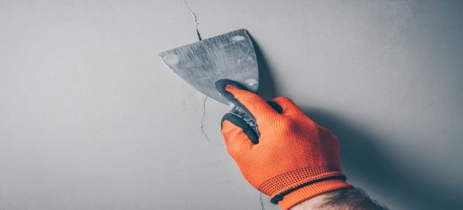 Quelqu'un réparant une fissure dans un mur en béton. 