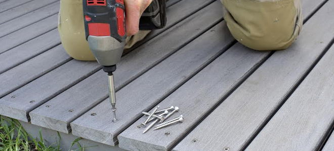 Someone using a screwdriver on a deck. 