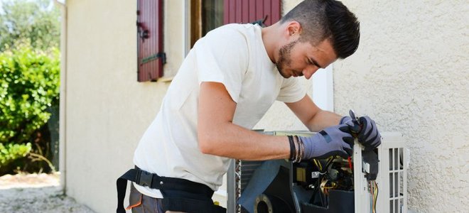 man working on an outdoor central air conditioning unit