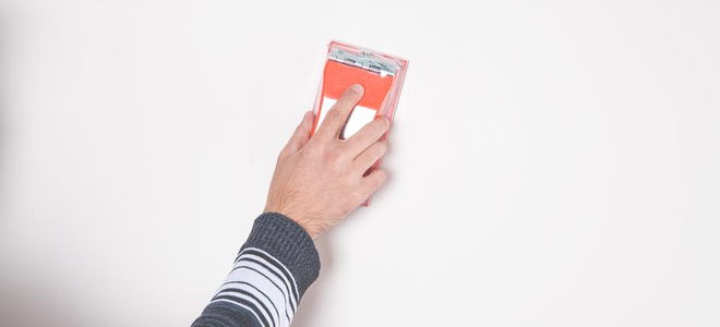 Someone using sandpaper on a white wall. 