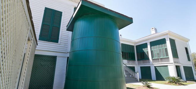 A green plastic rainwater cistern next to a building. 