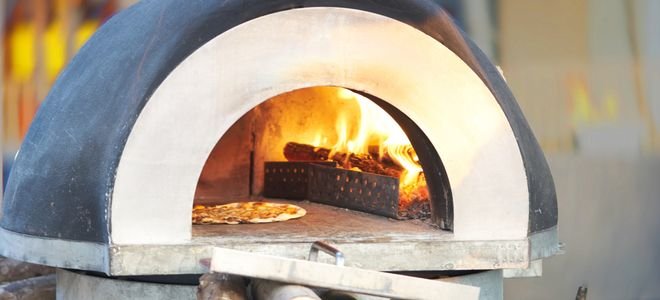 outdoor cement pizza oven with fire and pizza inside