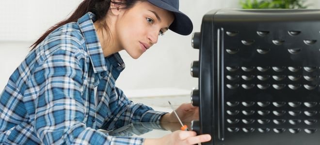 woman examining toaster oven with a screwdriver