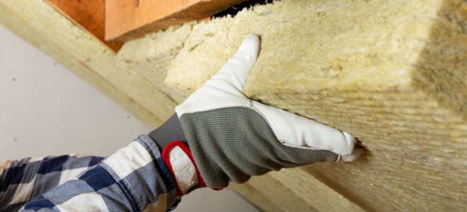 gloved hand installing batt insulation squares