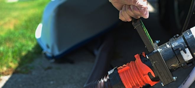 hands with tool opening RV water line to drain