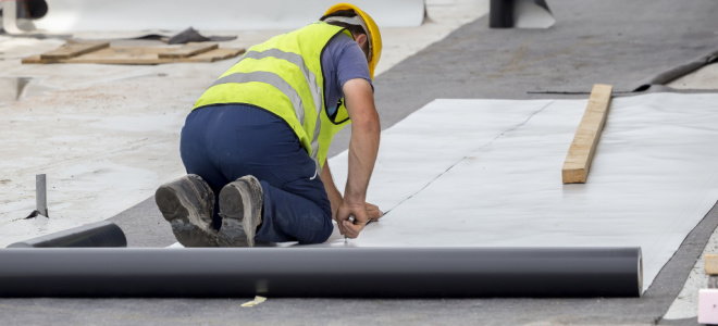 worker installing moisture barrier on foundation