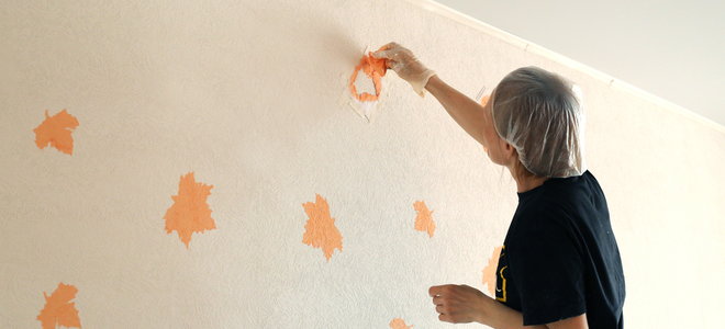 man painting leaf shaped stencils on a wall