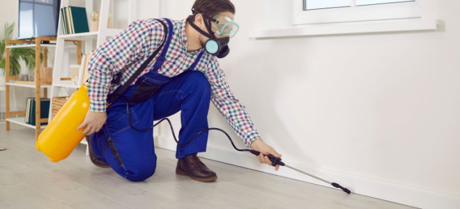 exterminator with protective gear spraying floor