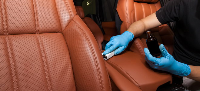 gloved hands applying leather car seat filler