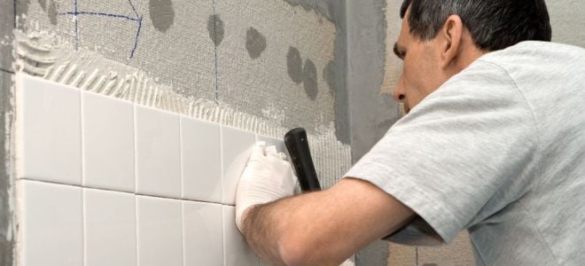 man installing tile on wall
