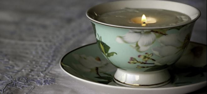 lit candle in a pretty teacup
