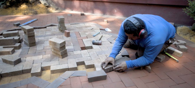 worker laying brick pavers