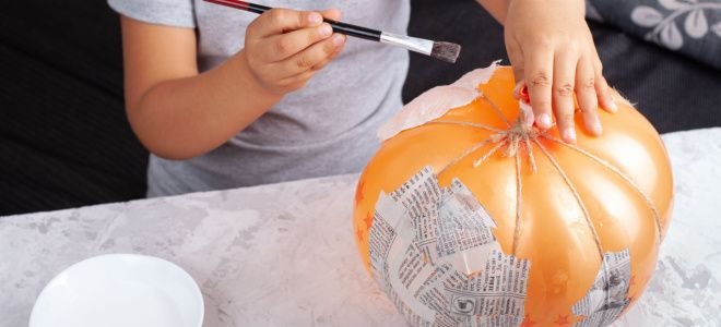 young person painting paper mache pumpkin