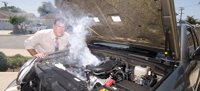 A man inspecting an overheating car engine