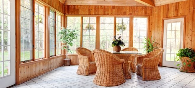 open wood sunroom with wicker furniture on tile