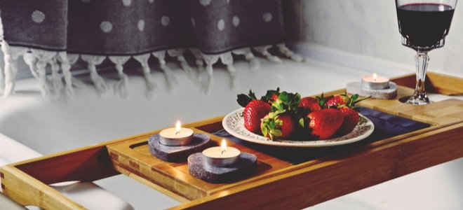 wooden bathtub tray with candles strawberries and wine