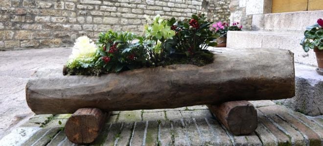 A rustic log planter on a deck. 