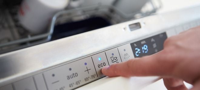 hand pushing buttons on energy efficient washing machine