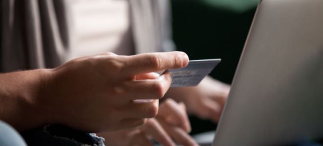 hand holding credit card near computer