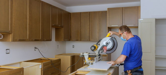 man using power saw in kitchen to cut board