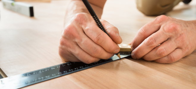hands marking a line on wood using a ruler