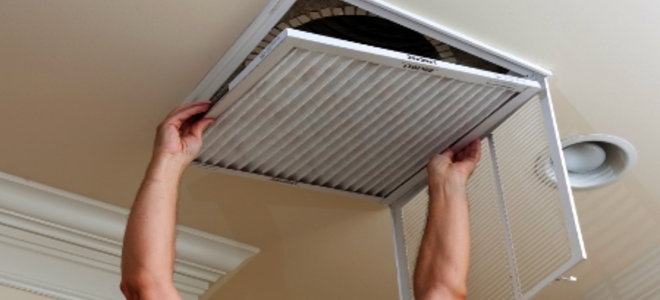 A man replacing an HVAC filter. 