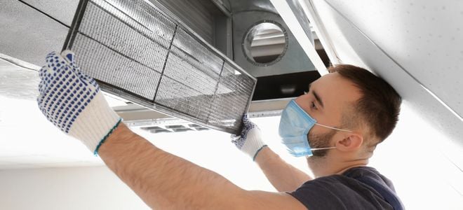 man checking long filter from HVAC duct