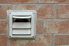An exterior dryer vent outside of a brick house.