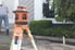 rotary laser level on tripod outside house with person in the background