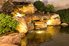 A backyard pond with lights and a waterfall