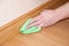 dusting wooden baseboard with cloth