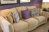 A beige couch with five throw pillows.