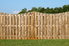 A wooden fence on a lush green landscape against a bright blue sky.