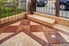 A beige and brown stamped concrete patio surrounded by a metal fence.